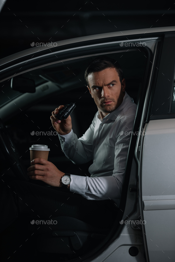 serious male undercover agent doing surveillance by binoculars and holding  paper cup of coffee Stock Photo by LightFieldStudios