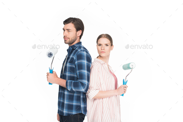 young couple with paint rollers standing back to back isolated on white background