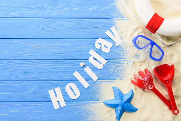Beach toys and Holiday inscription on blue wooden background
