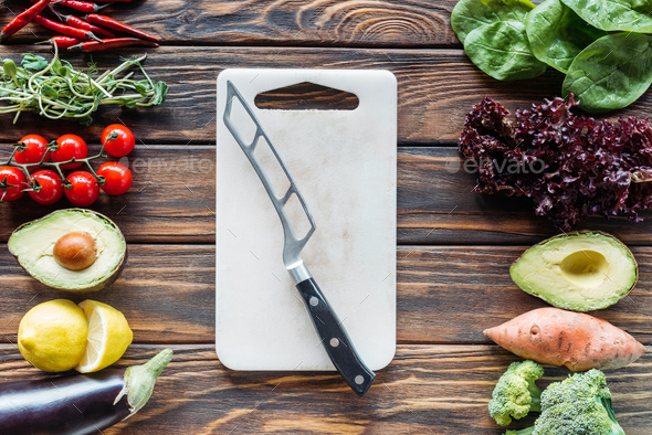 Fresh vegetables on woden cutting board with knife