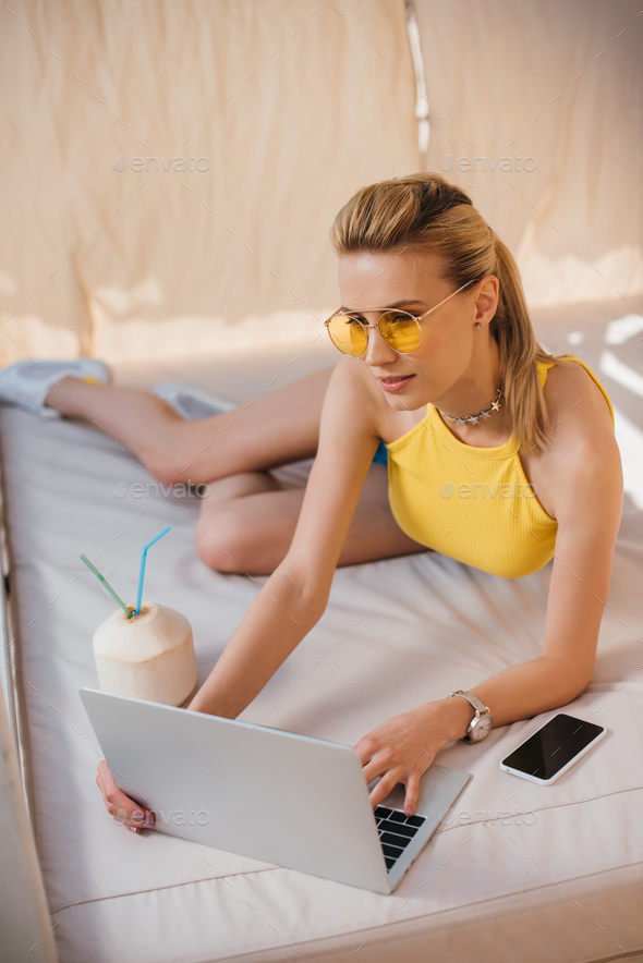 Confident woman wearing sunglasses using laptop while sitting on steps  Stock Photo - Alamy