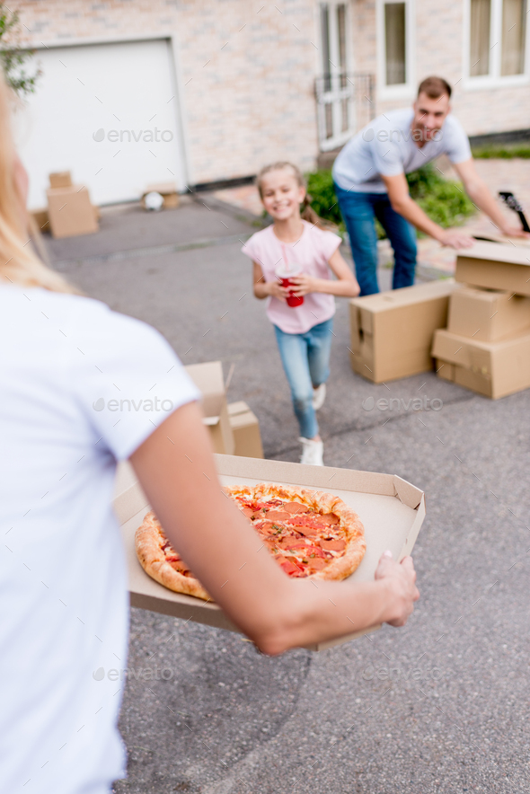 cropped image of woman holding pizza and daughter with cup of cola running to her