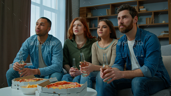 Four friends watch television with beer and pizza at home diverse multiethnic women men sport fans