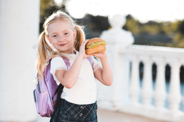 Happy pupil child girl eating burger at school - Stock Photo - Images
