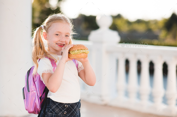 Happy pupil child girl eating burger at school - Stock Photo - Images