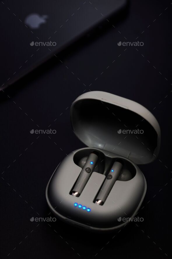 Vertical closeup of wireless Bluetooth earphones on a dark background