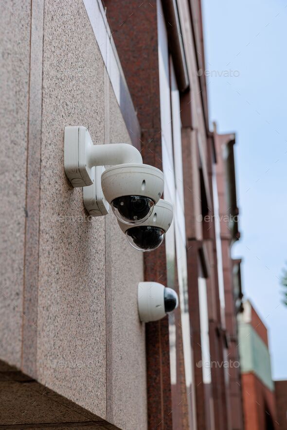Vertical shot of security cameras on the side of a building Stock Photo by wirestock