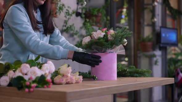 Bouquet with Pink Flowers and Green Coniferous Branches on Wooden Table in Workshop with alt