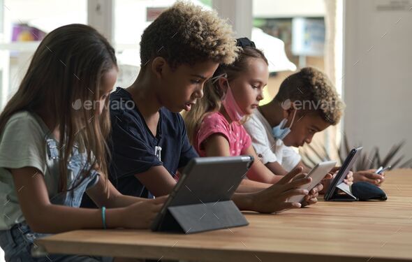 Pretty multi-national kids playing at tablet at home - virtual gadgets addiction problem concept