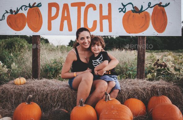 Young mom with her son sitting on a hale bale at a Pumpkin patch in Bonita Springs, Florida