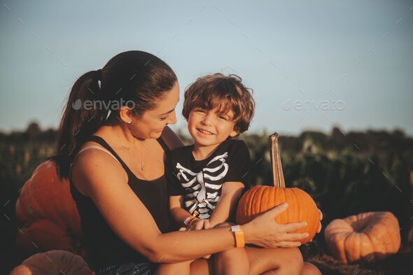 Young mom with her son sitting on a hale bale at a Pumpkin patch in Bonita Springs, Florida
