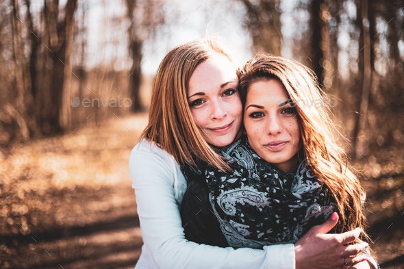 Two young female friends posing for smartphone selfie in park stock photo