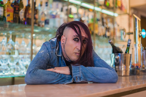 Portrait of an eccentric rocker with a denim jacket. He has long purple ...