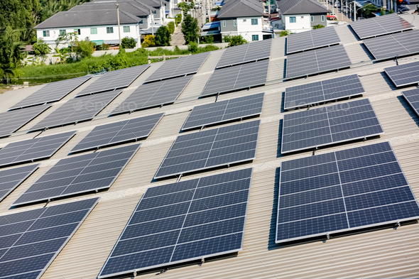 Solar panel installer installing solar panels on roof of warehouse ...