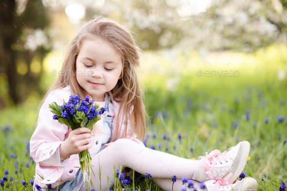 Cute smiling kid girl holding flowers over nature sunny background - Stock Photo - Images