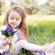 Cute smiling kid girl holding flowers over nature sunny background - PhotoDune Item for Sale