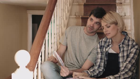 Adult couple looking at colour swatch on staircase in new home