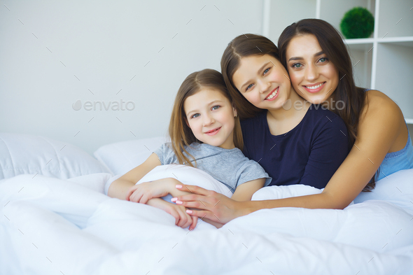 Woman and young girl lying in bed smiling Stock Photo by maksymiv ...