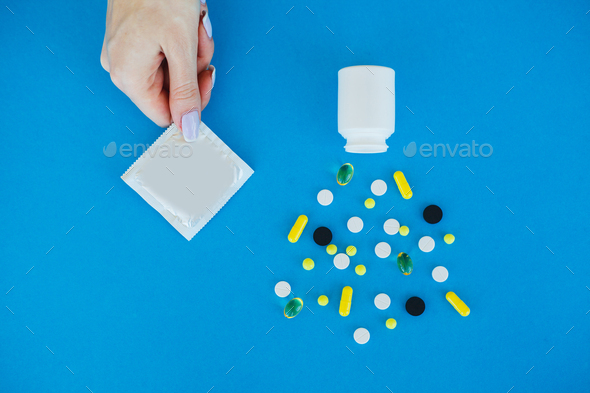 Antibiotics from venereal diseases. Concept of safe sex. Pills and condom lie on a blue Background