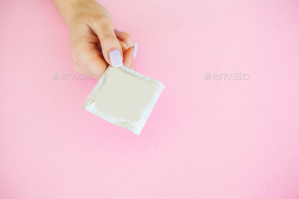 Antibiotics from venereal diseases. Concept of safe sex. Pills and condom lie on a pink Background