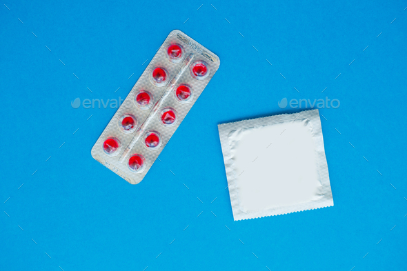 Antibiotics from venereal diseases. Concept of safe sex. Pills and condom lie on a blue Background