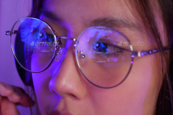 Female gamer wearing glasses for reducing eye strain blurred vision at home