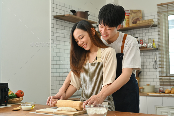 Loving young husband and wife have fun making bread in kitchen, enjoying spending weekend time - Stock Photo - Images