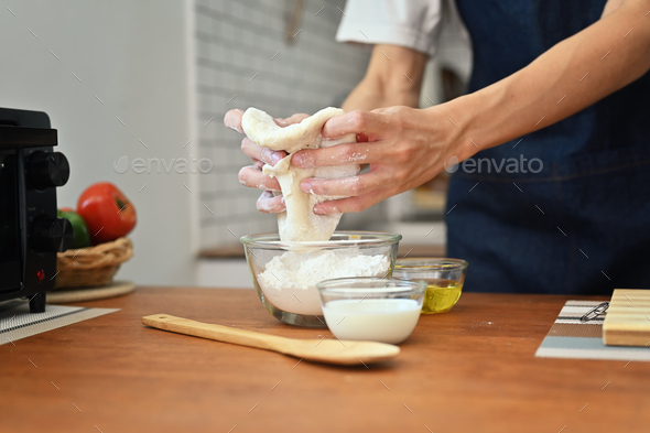 Man wearing aprons hands kneading dough on wooden table, preparing homemade pastry. - Stock Photo - Images