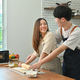 Cheerful young couple wearing aprons preparing homemade pastry, enjoying leisure time. - PhotoDune Item for Sale