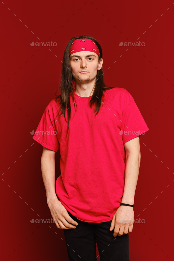 Portrait of positive guy wearing red band on head and shirt, standing against red wall