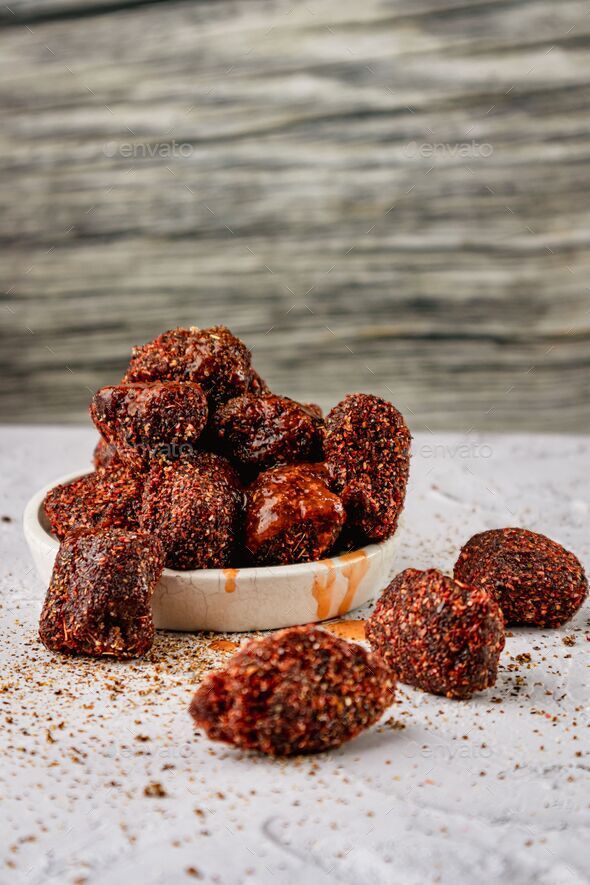 Vertical closeup of natural tamarind with chili powder and chamoy on