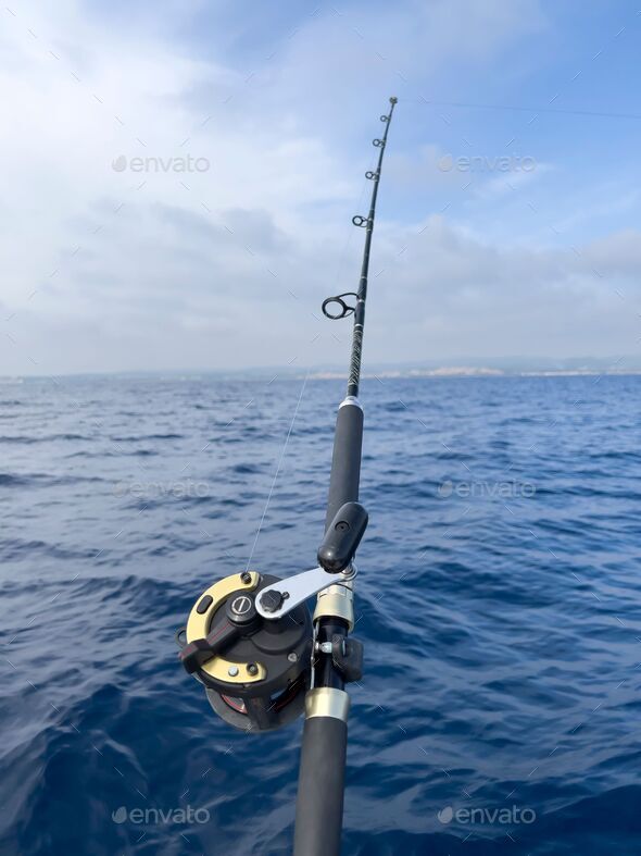 Fishing rod and reel anchored to the ship looking for a big catching in a  deep seascape offshore Stock Photo by wirestock