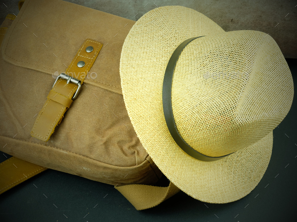 Closeup of brown sling bag and hat on the ground
