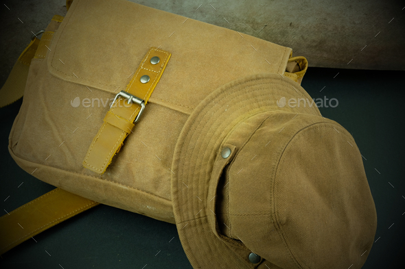 Closeup of brown sling bag and hat on the grou