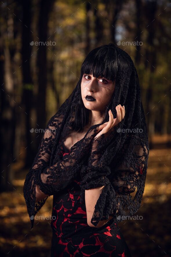 Vertical shot of a Caucasian pretty female in a gothic style black dress  Stock Photo by wirestock