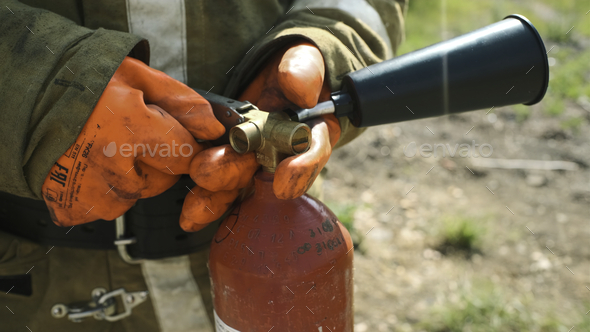 Close-up of firefighter with fire extinguisher. Clip. Firefighter picks up fire extinguisher and - Stock Photo - Images
