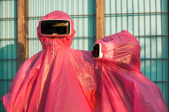 Closeup shot of two people in pink plastic raincoats and VR headsets