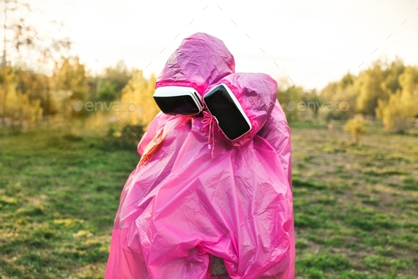 Closeup shot of two people hugging each other in pink plastic raincoats and VR headsets