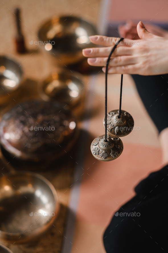 Close-up of a woman's hand holding Tibetan bells for sound therapy. Tibetan  cymbals Stock Photo by Lobachad