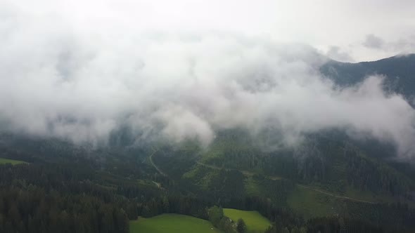 Aerial Shot in Clouds, Camera Is Over Green Mountains and Fields
