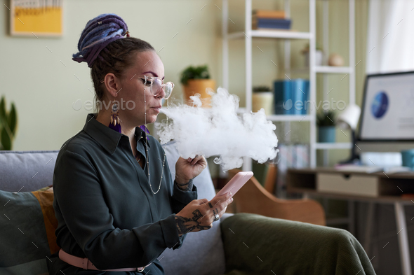 Young businesswoman scrolling in mobile phone and smoking