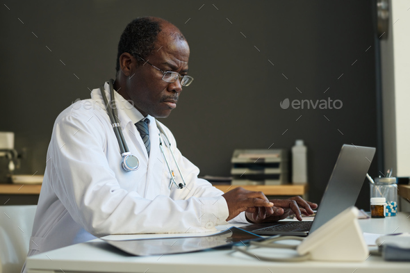 Mature African American virtual health assistant typing on laptop keyboard