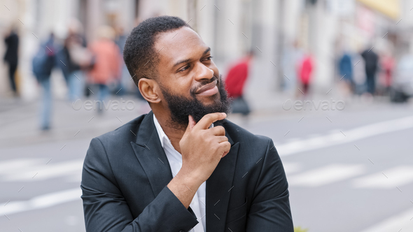 Close up portrait bearded ethnic man outdoors African American businessman looking away thinking