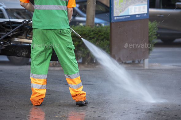 Maintenance worker cleaning up a park with a pressurized bleach water gun