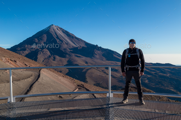 Beautiful shot of a male standing on a balcony facing the Pico de Orizaba Volcano in Mexico