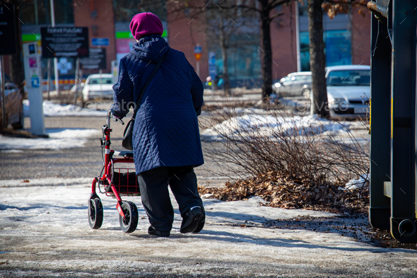 Elderly woman walking with a walker down the snow-covered street