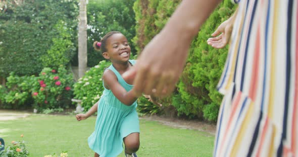 African american mother embracing her two smiling daughters in garden alt