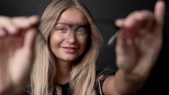 Blond Woman Holding Pair Of Glasses alt