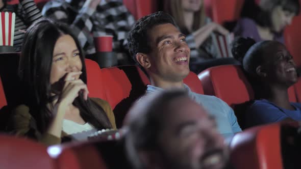 Mixed Race Couple Laughing While Watching Movie alt