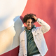 Happy African American teen guy laughing standing at red wall. Vertical - PhotoDune Item for Sale
